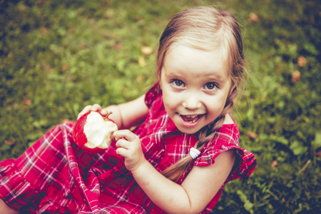 Cute little girl with apples in a green grass.の写真素材