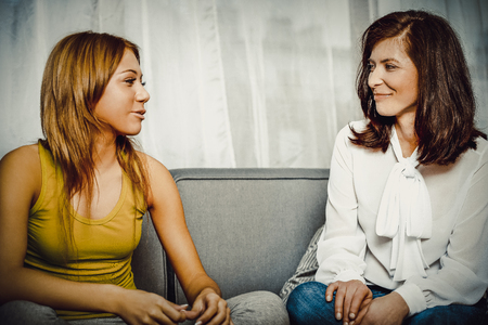 Mother and doughter sitting on sofa.の写真素材