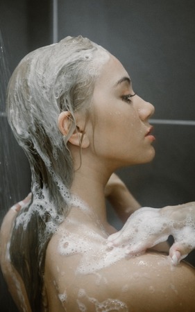 Beautiful young woman taking shower in bathroom.の写真素材