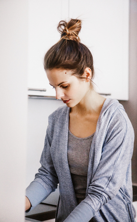 Cute lovely young woman standing and washing dishesの写真素材