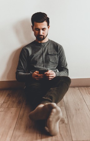 Happy man using mobile phone at homeの写真素材