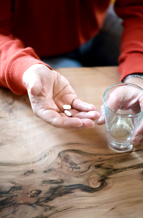 Medical pill on the wrinkly hand of an old man.の写真素材