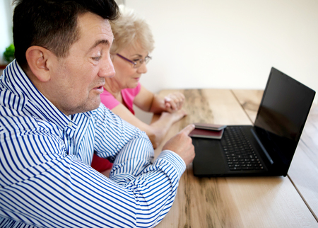 The senior couple surfing the internet with laptop computerの写真素材