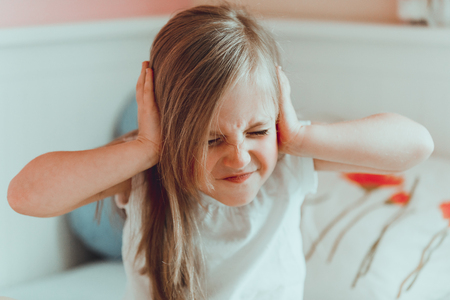Child girl clogs her ears and closing eyes.の写真素材
