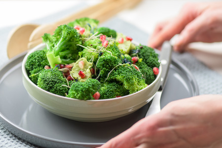 Broccoli salad with pomegranate and guacamole - hands holding healthy mealの写真素材