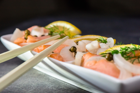 Salmon in a marinade of lemon juice with green onion and pepper - healthy food - closeupの写真素材