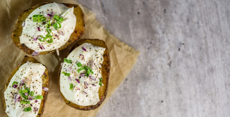 Baked potatoes with curd cheese, red onion and chive - closeup - banner - copy spaceの写真素材