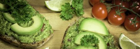 Slice of bread with guacamole made from avocado, tomato, lime, poarsley and garlic - close up  - banner designの写真素材