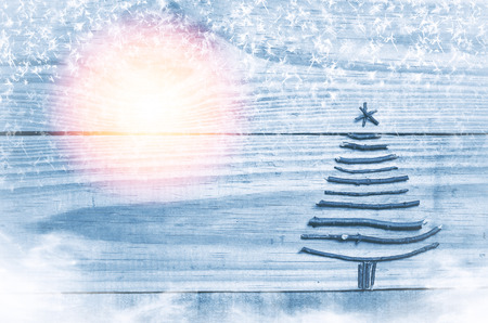 Christmas tree made from dry sticks on wooden, blue background. Snow, snow flaks, sun image. Christmas tree ornament.の写真素材