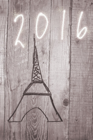 Eiffel Tower arranged from wooden sticks.Date 2016 written on grey background.