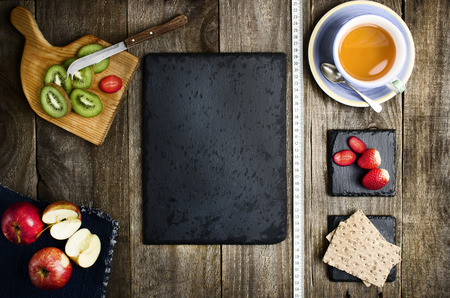 Rice bread, tea and healthy fruits on wooden background. Black empty stone in middle with copy space. Diet concept. Healthy food, diet conception.の写真素材