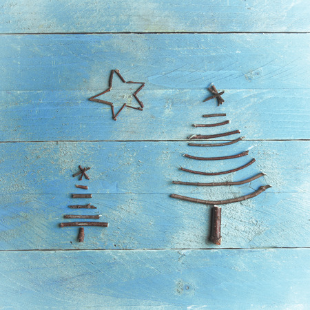 Two Christmas trees and star made from dry sticks on wooden, blue background.の写真素材