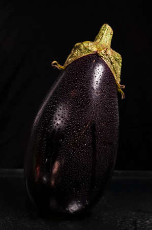Close up wet eggplant isolated on black background.