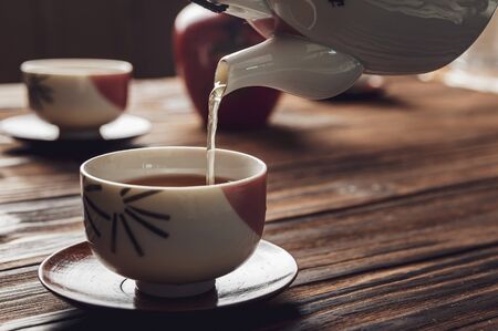 Pouring japanese tea into asian porcelain cup on wood tableの素材 [FY310146815836]