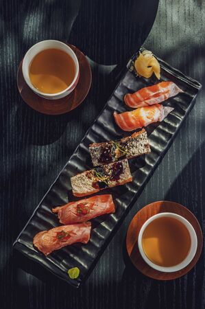 Top view of variety sushis japanese food and tea on a black tableの写真素材