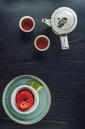 Top view of a black table with a salmon tartare and japanese teaの写真素材