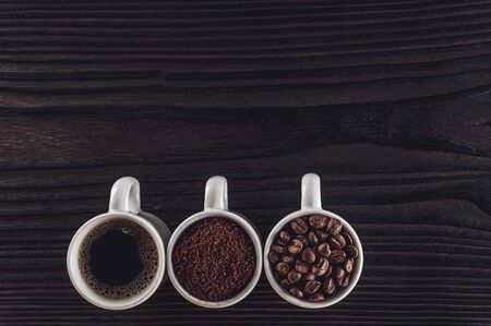 Brazialian coffee in liquid, powder and beans state on a black wood - Top viewの写真素材