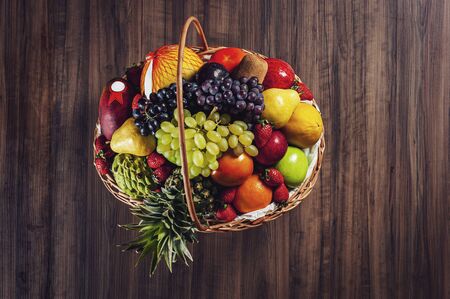 Top view of a basket and fresh fruits on wooden tableの写真素材