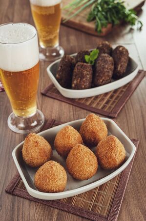 Brazilian appetiser deep fried coxinha de frango, kibbe and two glass of beerの写真素材