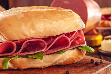 Mortadella sandwich with arugula and black pepper on wood cutting board - Close-upの写真素材