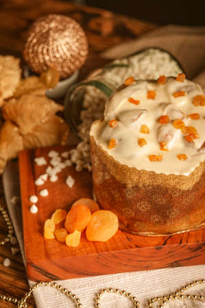 White chocolate panettone with dried apricot on wooden table with christmas ornaments