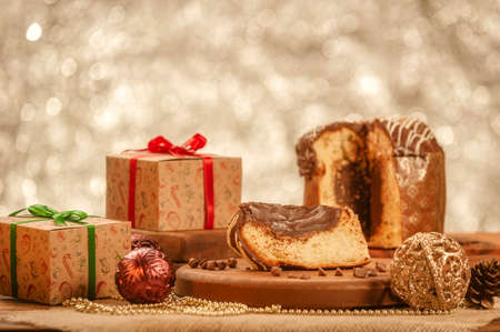 Slice of chocolate panettone on wooden cutting board with christmas ornamentsの写真素材