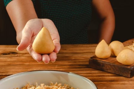 Hands of woman preparing brazilian croquette on a wooden kitchen tableの写真素材