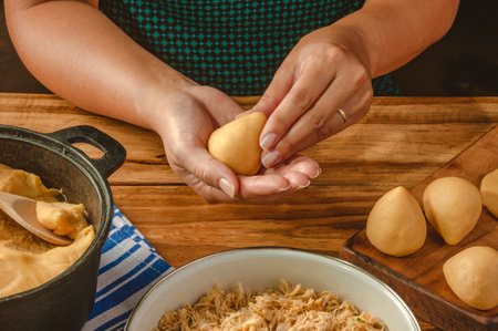 Hands of woman preparing brazilian croquette on a wooden kitchen tableの写真素材