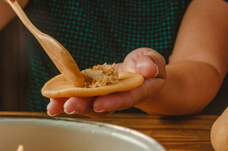 Hands of woman preparing brazilian croquette (chicken coxinha) on a wooden kitchen table - Close-upの写真素材