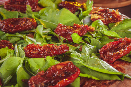 Brazilian pizza with tomato sauce, mozzarella, arugula, dried tomatoes and oregano.の写真素材