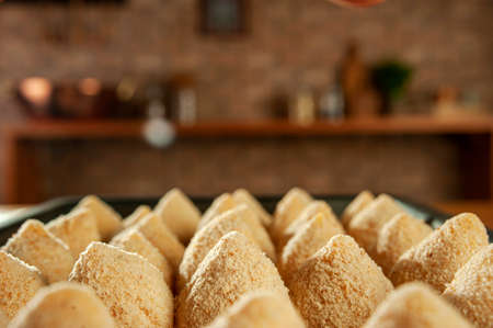 Breading brazilian croquette (chicken drumstick) on kitchen bricks wall background.