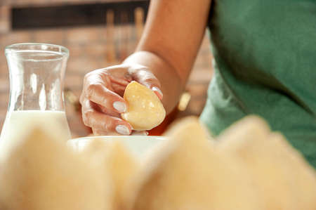 Woman hands breading brazilian chicken croquette on a wooden table.の写真素材