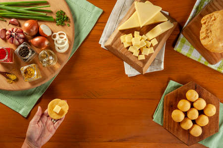 WomanÂ´s hand preparing Brazilian cheese stuffed croquette on a wooden table. Top view.の写真素材