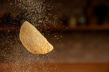 Uncooked Brazilian croquette stuffed with ground beef been breading with breadcrumbs.