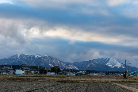 Landscape view of snow mountain and village with cloudy sky in winter seasonの写真素材