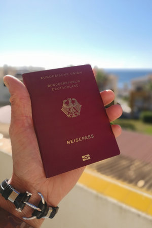Man holding German passport in hand with sea in backgroundの写真素材