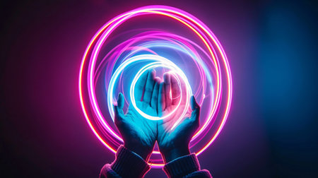 Hands with glowing neon circle on dark background.の素材