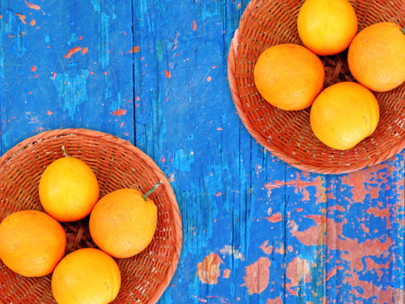 Oranges in a wicker basket on a blue wooden background.の写真素材