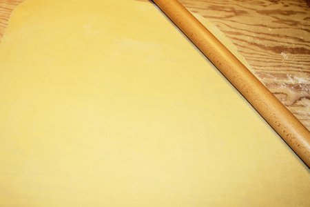 dough being flattened on a wooden cutting boardの写真素材
