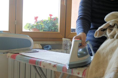 Ironing a towel with a steam iron on an ironing boardの写真素材