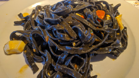 Black spaghetti on a white plate in a restaurant, closeup of photoの写真素材