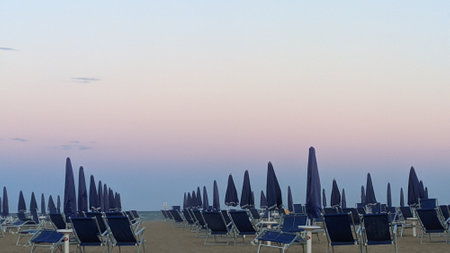 Beach with umbrellas and sun loungers at sunsetの写真素材