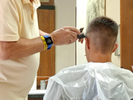 Hairdresser cutting hair of a boy in a barbershopの写真素材