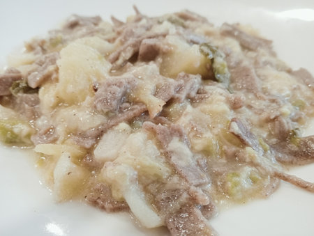 Fried potatoes with meat on a white plate, close-up