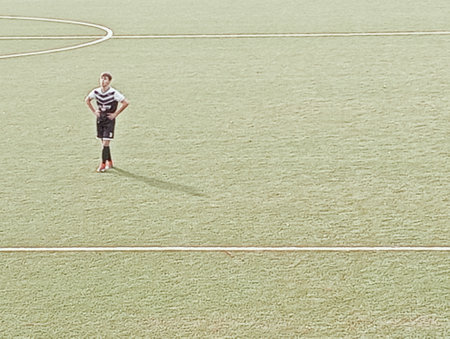High angle view of a young soccer player standing on the field.の写真素材