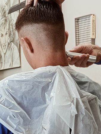 Barber trimming the hair of a man in a barbershopの写真素材