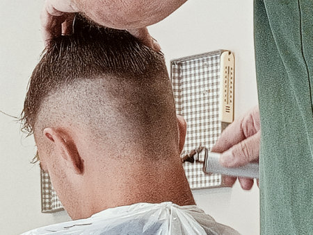 Hairdresser trimming man's hair in barbershopの写真素材