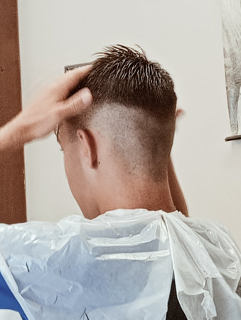 Hairdresser trimming client's hair in barbershopの写真素材