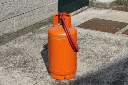 Orange gas cylinder in front of the entrance to the house, on the streetの写真素材