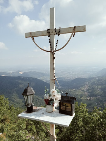 Wooden cross with flowers and lantern on top of the mountain.